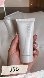 Hand holding a white skincare tube